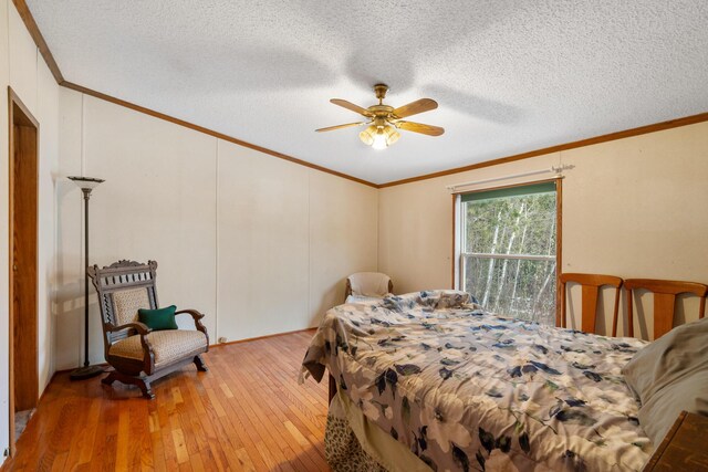 bedroom featuring hardwood / wood-style floors, a textured ceiling, a ceiling fan, and ornamental molding