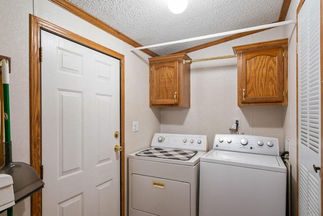 washroom with cabinet space, washer and dryer, a textured ceiling, and crown molding