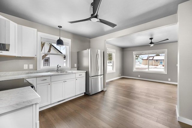 kitchen featuring baseboards, freestanding refrigerator, dark wood-style floors, white cabinetry, and a sink