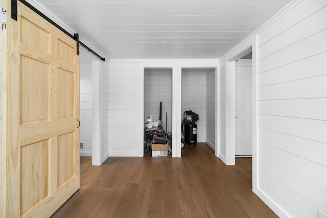 corridor with dark wood-type flooring and a barn door