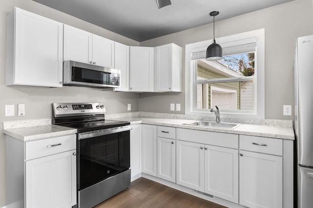 kitchen with visible vents, a sink, stainless steel appliances, dark wood-type flooring, and white cabinets