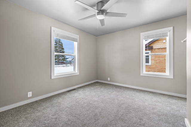 carpeted spare room with visible vents, baseboards, and ceiling fan