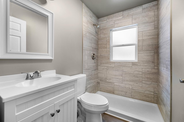 full bathroom with vanity, toilet, and a tile shower