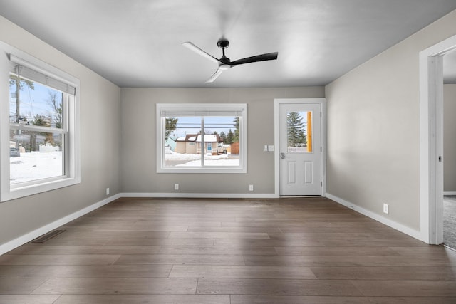 interior space with a ceiling fan, plenty of natural light, visible vents, and dark wood-style flooring