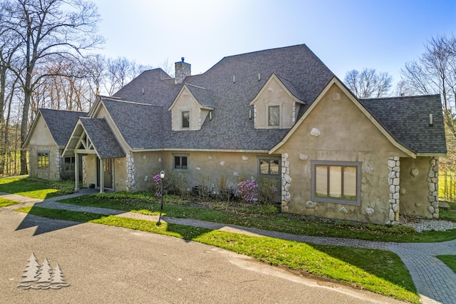 view of front of property with stone siding, stucco siding, a chimney, and roof with shingles