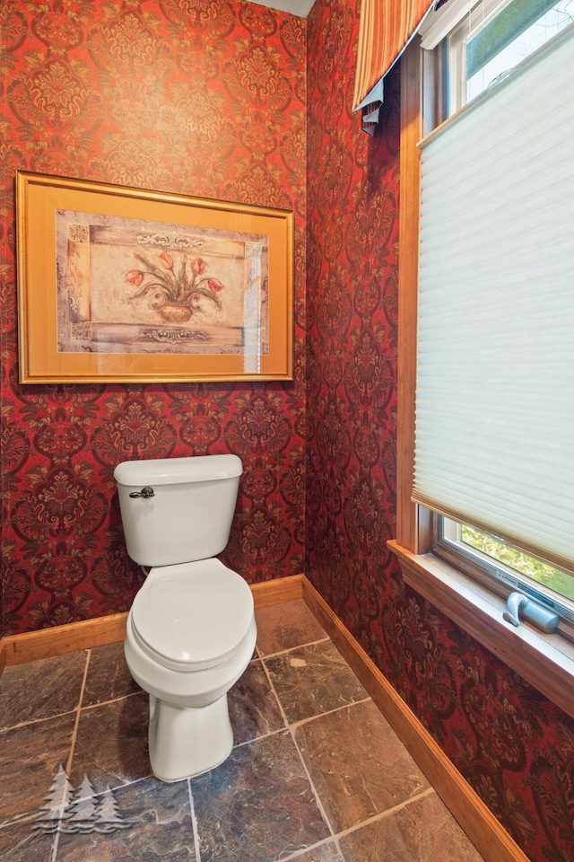 bathroom featuring a healthy amount of sunlight, wallpapered walls, and baseboards