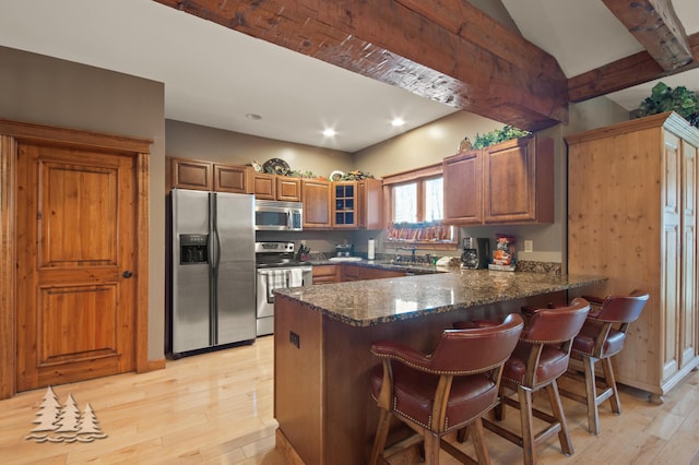 kitchen with light wood-type flooring, brown cabinets, appliances with stainless steel finishes, and a peninsula