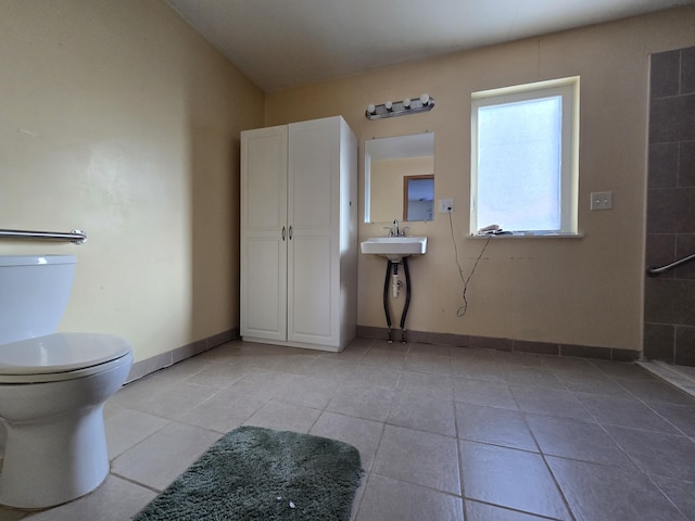 bathroom featuring tile patterned flooring, toilet, baseboards, and a sink