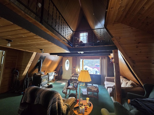 living area featuring plenty of natural light, wood walls, a wood stove, and a high ceiling