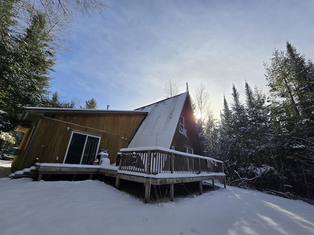 snow covered rear of property with a wooden deck