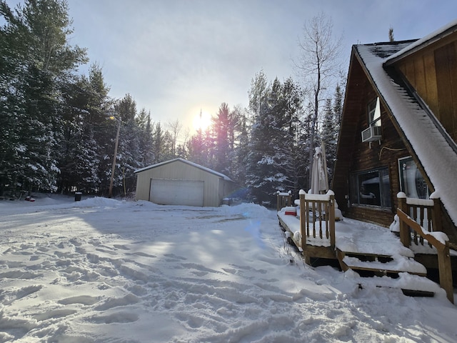 yard covered in snow featuring cooling unit, a detached garage, and an outdoor structure