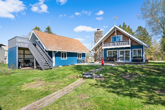 rear view of property with a balcony, a chimney, stairway, a yard, and a patio area