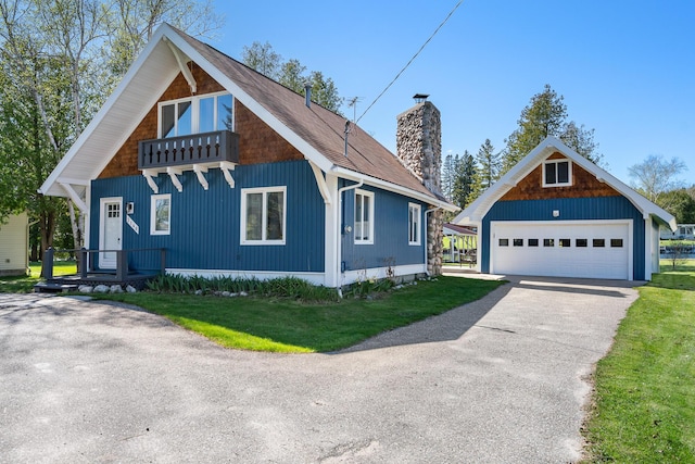 view of side of property featuring a detached garage, a chimney, covered porch, an outdoor structure, and a yard