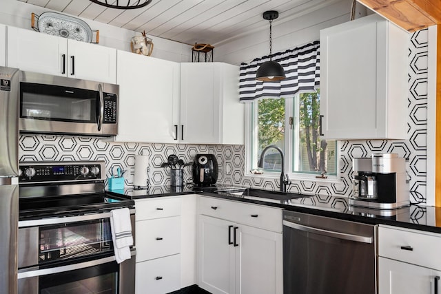 kitchen with a sink, tasteful backsplash, stainless steel appliances, dark countertops, and white cabinets