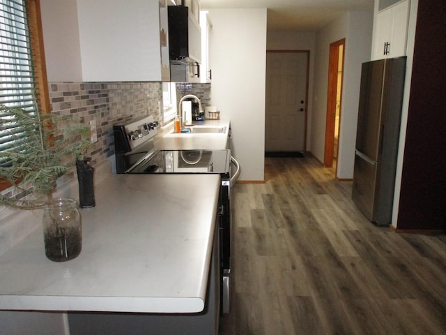 kitchen featuring electric range, a sink, wood finished floors, freestanding refrigerator, and white cabinets