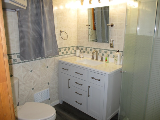 full bathroom with visible vents, toilet, tile walls, and vanity