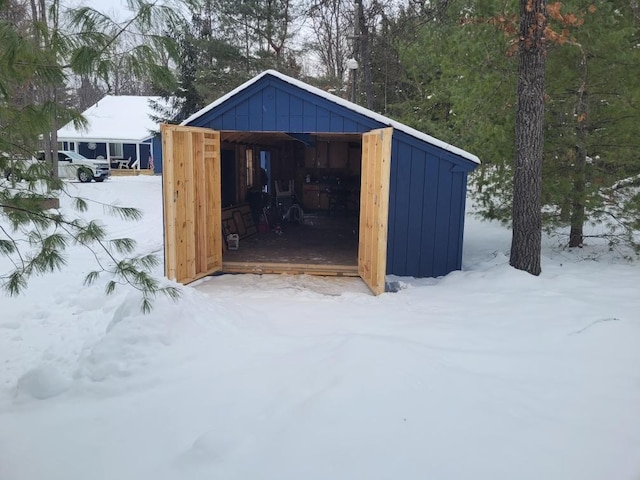 snow covered structure featuring an outbuilding