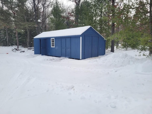 snow covered structure with an outbuilding