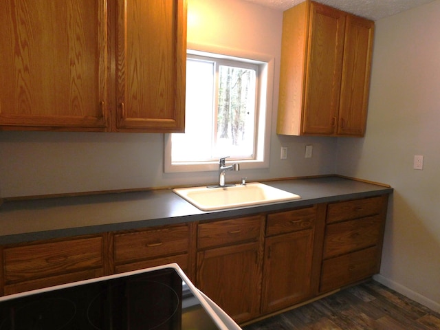 kitchen featuring a sink, brown cabinets, dark countertops, and dark wood finished floors