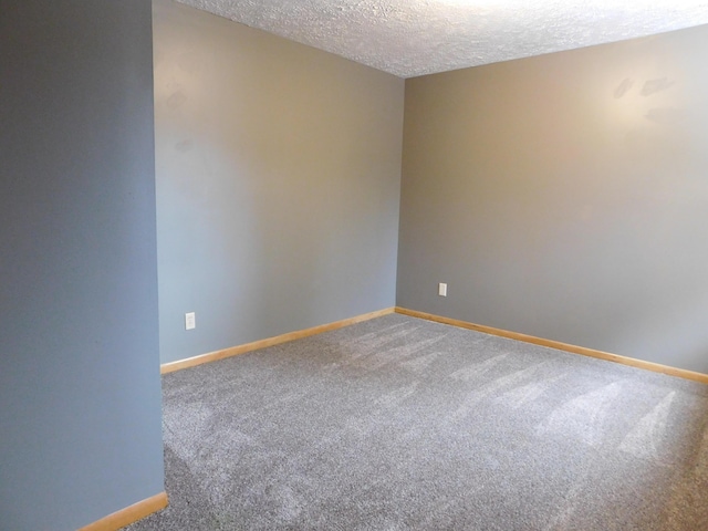 unfurnished room with a textured ceiling, carpet, and baseboards