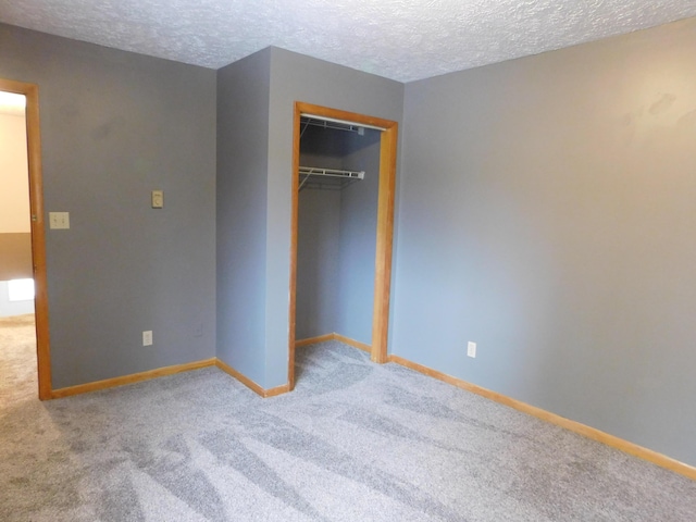 unfurnished bedroom with baseboards, carpet floors, a textured ceiling, and a closet