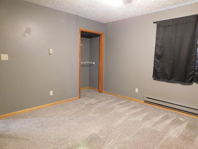 unfurnished bedroom with a baseboard heating unit, baseboards, carpet, a closet, and a textured ceiling