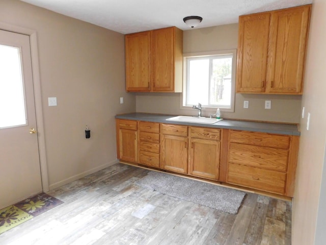 kitchen with brown cabinets, baseboards, light wood finished floors, and a sink