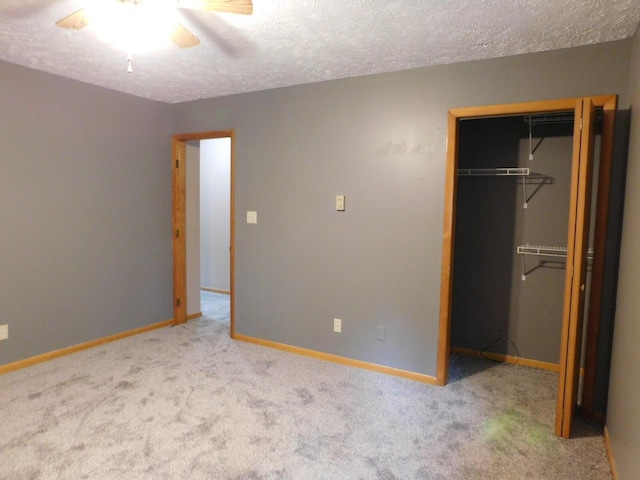 unfurnished bedroom with carpet, baseboards, ceiling fan, a closet, and a textured ceiling