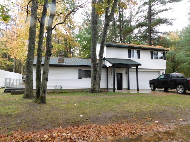 traditional home with a front lawn, an attached garage, a chimney, and a shingled roof