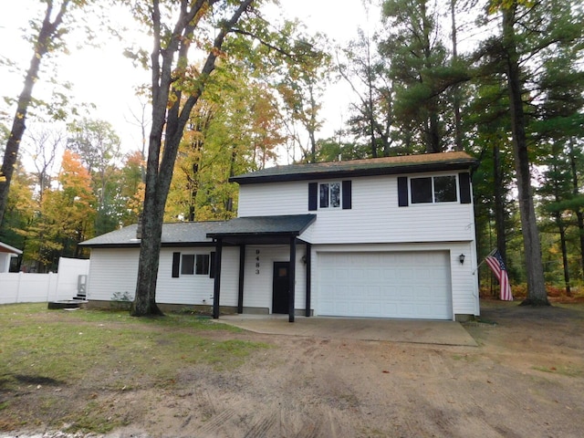 traditional-style house featuring driveway, an attached garage, and fence