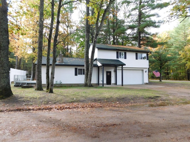 traditional-style house featuring concrete driveway, a chimney, and a garage