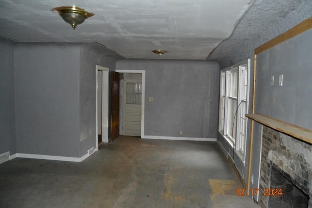 spare room with baseboards, concrete flooring, and a lit fireplace