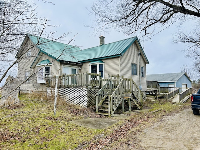 back of house with a wooden deck, metal roof, a chimney, and stairway