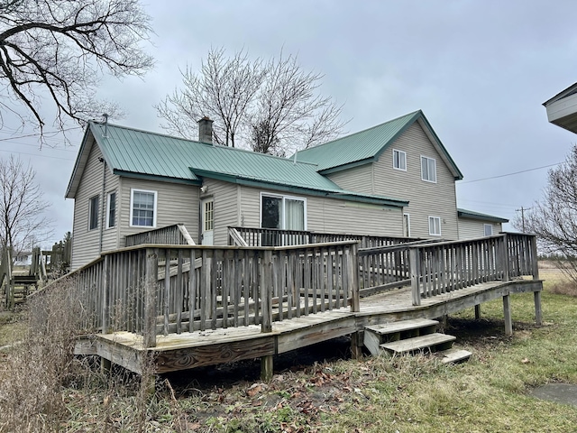 rear view of house with a deck, a chimney, and metal roof