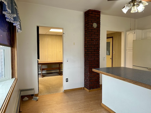 kitchen with dark countertops, light wood-style flooring, freestanding refrigerator, white cabinetry, and a baseboard radiator