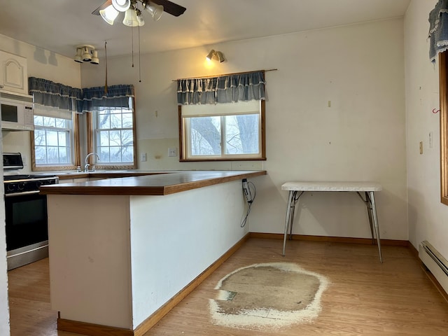 kitchen with a wealth of natural light, light wood-style flooring, gas stove, and white microwave