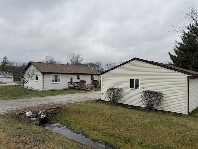 rear view of house featuring a lawn and driveway