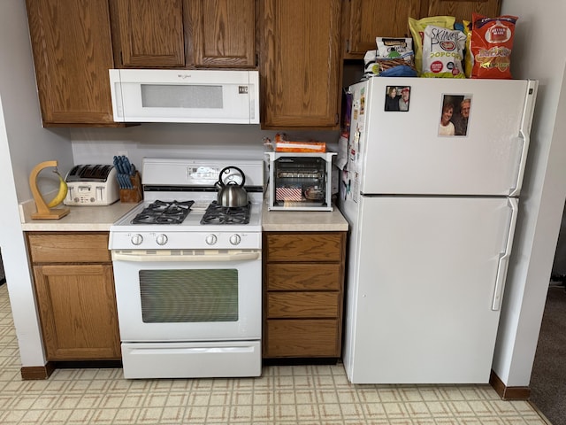 kitchen with white appliances, light floors, baseboards, light countertops, and brown cabinets