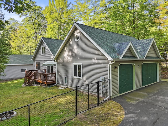 view of side of home with a wooden deck, a lawn, fence private yard, and a shingled roof