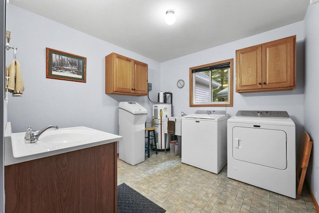 clothes washing area featuring a sink, cabinet space, water heater, and washing machine and clothes dryer