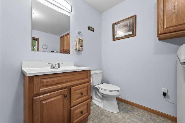 bathroom featuring baseboards, toilet, and vanity