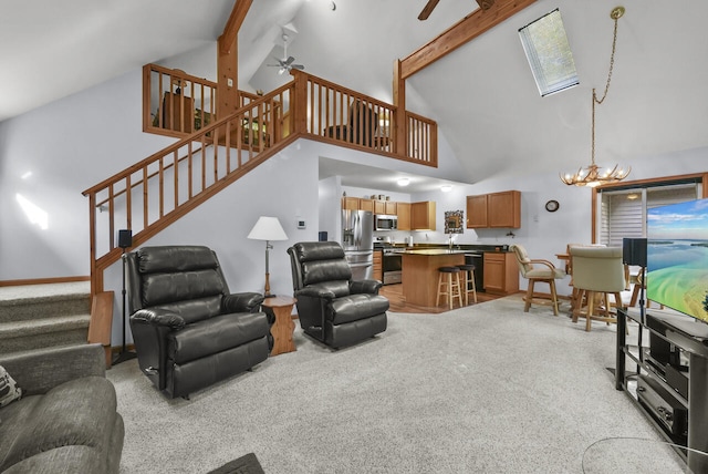 living room featuring beamed ceiling, stairs, light carpet, ceiling fan with notable chandelier, and high vaulted ceiling