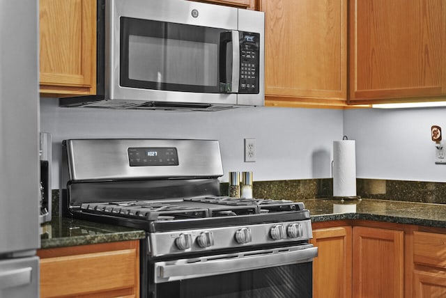 kitchen with dark stone countertops and appliances with stainless steel finishes