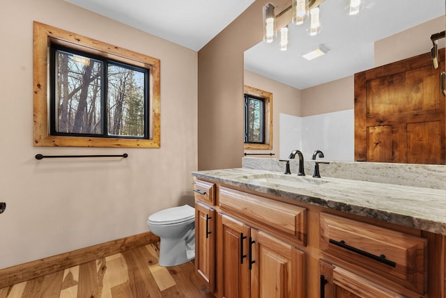 bathroom featuring toilet, vanity, baseboards, and wood finished floors