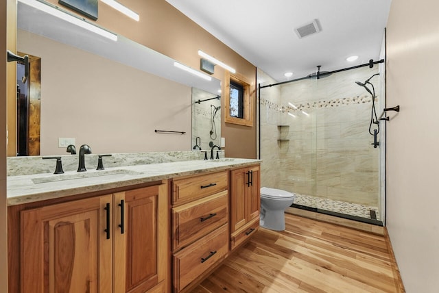 bathroom with a stall shower, wood finished floors, visible vents, and a sink