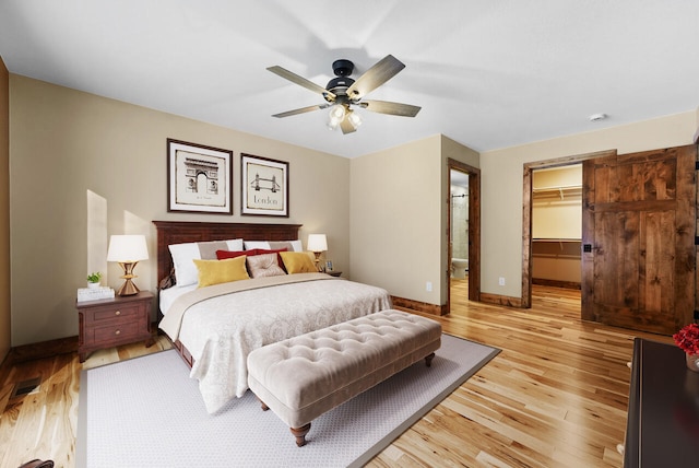 bedroom featuring a spacious closet, visible vents, ceiling fan, baseboards, and light wood-style floors