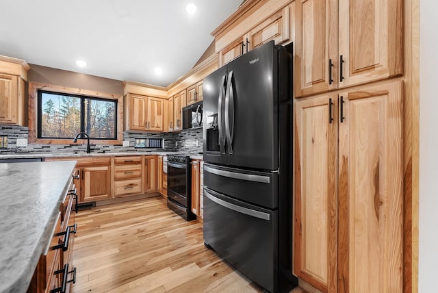 kitchen with black appliances, light wood-style flooring, backsplash, and a sink