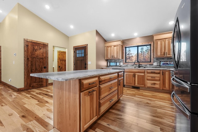 kitchen with light wood-style flooring, a sink, freestanding refrigerator, light countertops, and lofted ceiling