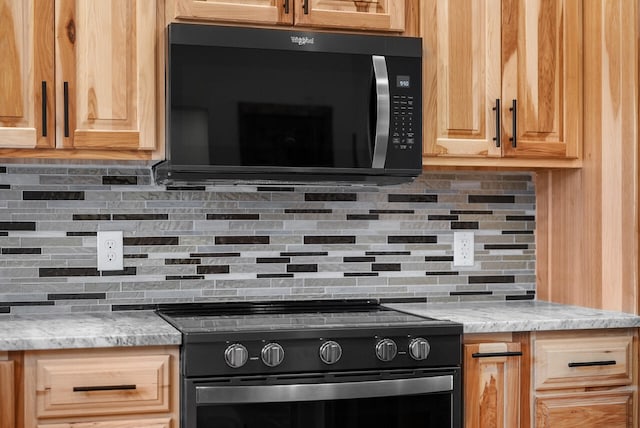 kitchen with light stone counters, black / electric stove, backsplash, and light brown cabinetry