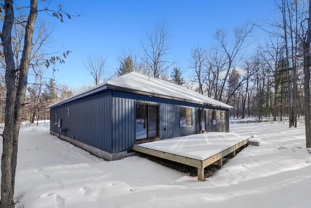 snow covered back of property featuring a wooden deck